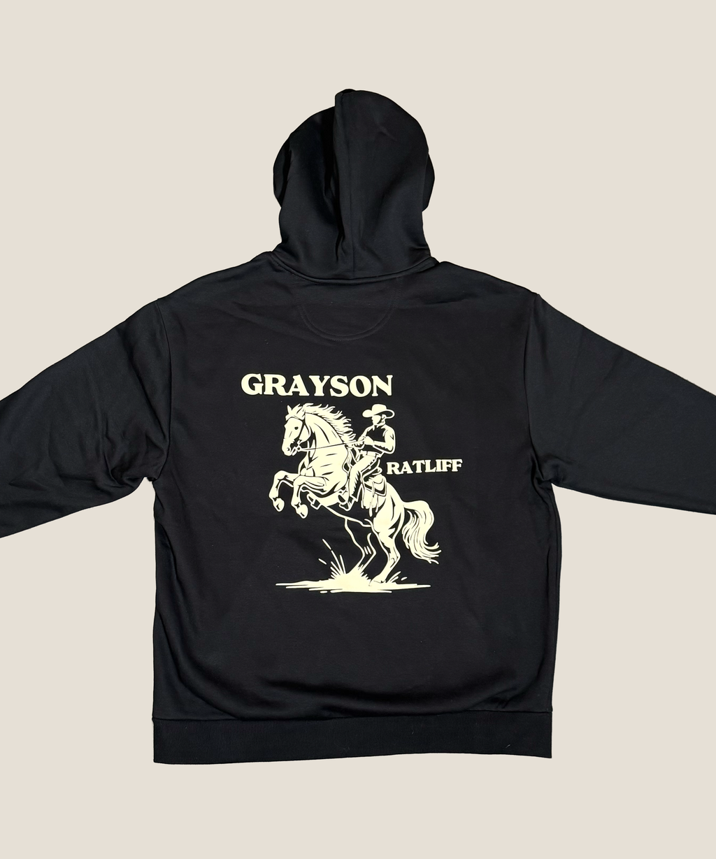 Black hoodie with a horse and rider graphic and text on the back against a beige background